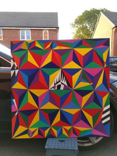 The canvas standing outdoors in front of a car, showing its full square composition in daylight.